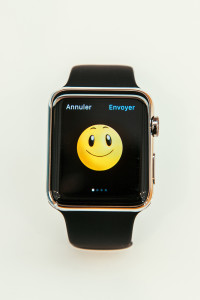 PARIS FRANCE - APR 10 2015: New wearable computer Apple Watch smartwatch displaying the new Smile Emoji. Apple Watch incorporates fitness tracking and health-oriented capabilities and integration with iOS Apple products and services