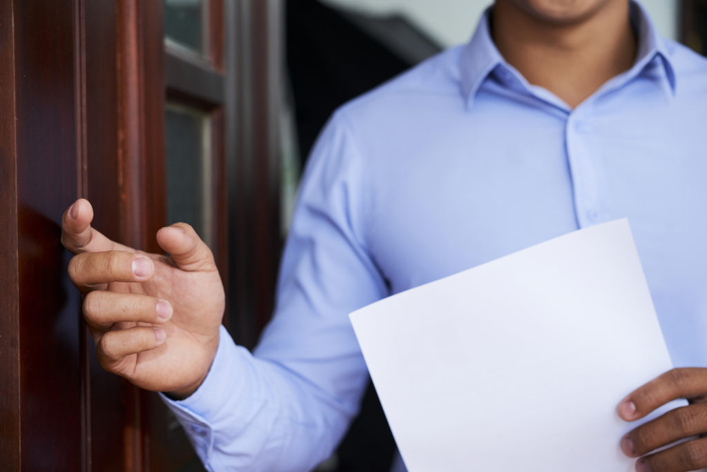 Young man in blue shirt knocking on the wooden door asking for coming in employer office for interview