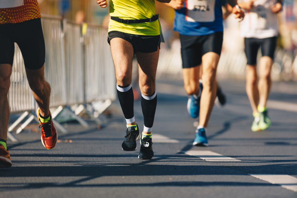 Marathon running race, people feet on autumn road. Runners run urban marathon in the the city