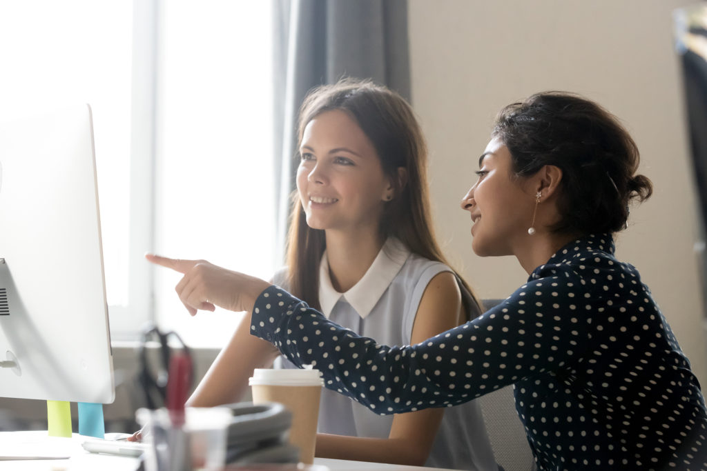 Happy caucasian intern listening to indian mentor explaining com